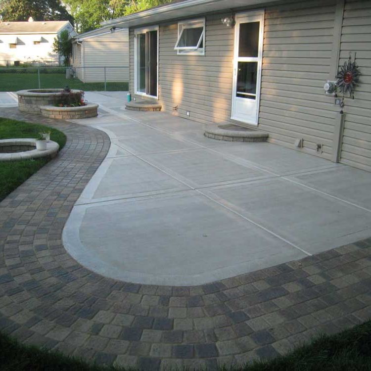 A stamped concrete patio with an outline in pavers